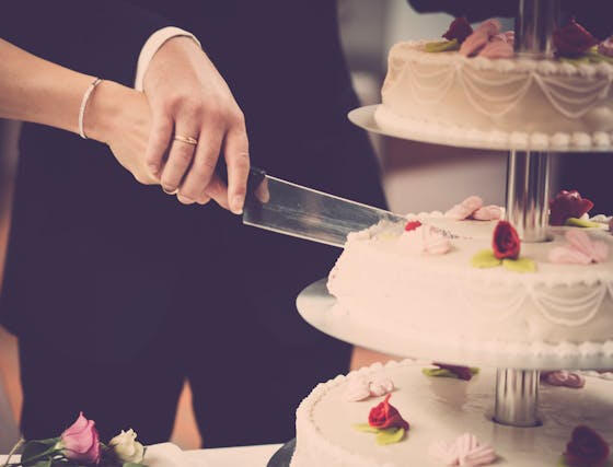 Bride and Groom cutting wedding cake hand over hand
